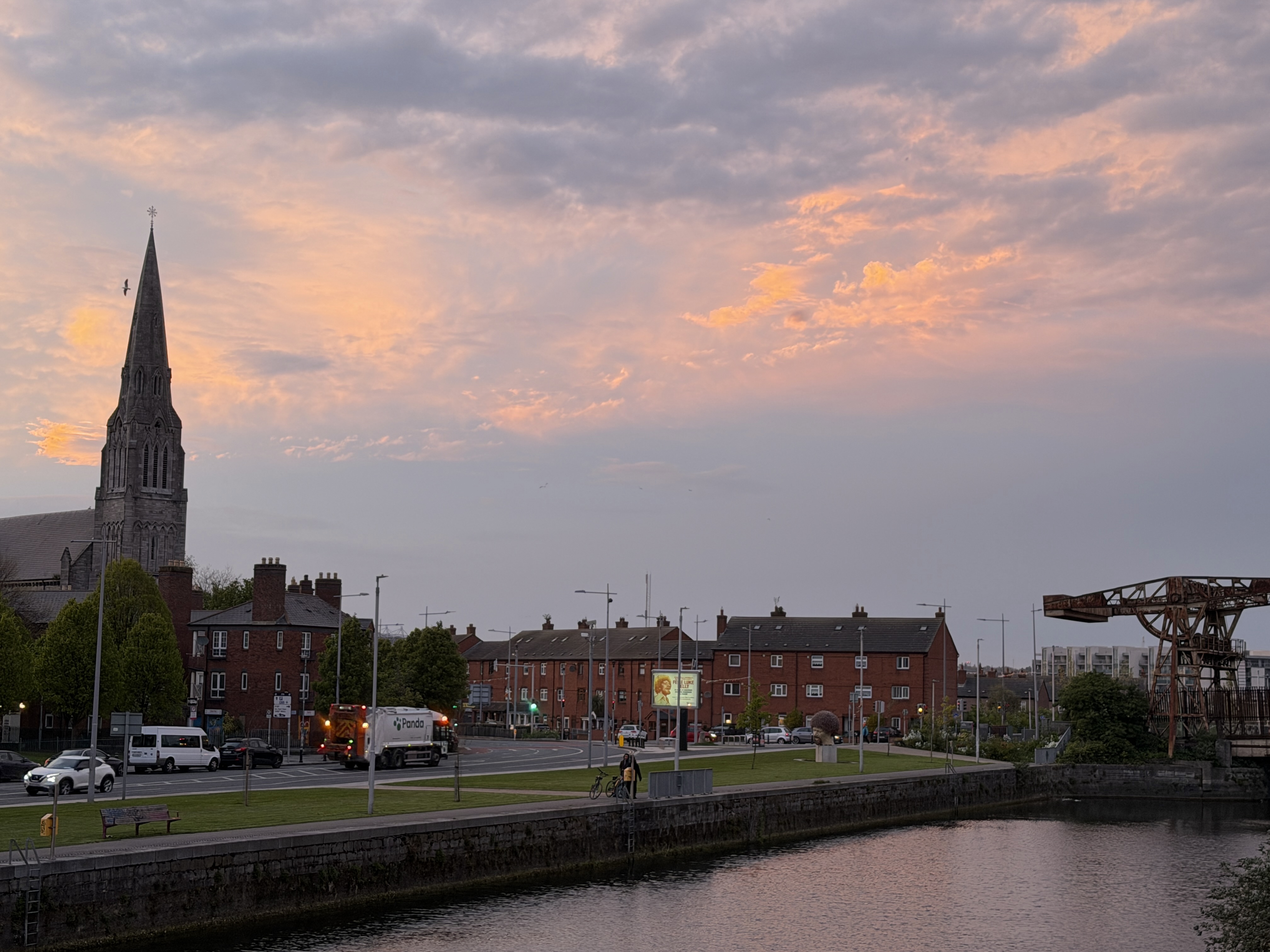 Warm sunset clouds above a Dublin waterside street and church spire.